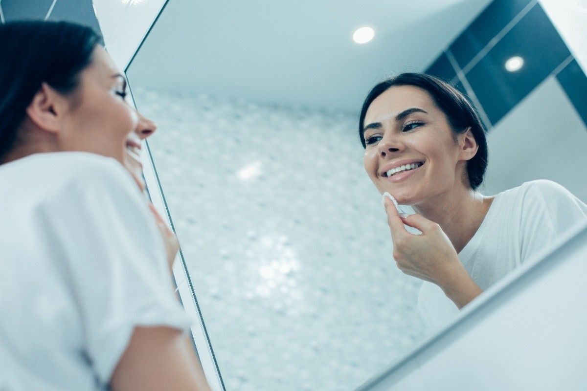 Woman smiling while checking her teeth in mirror before cosmetic veneer treatment