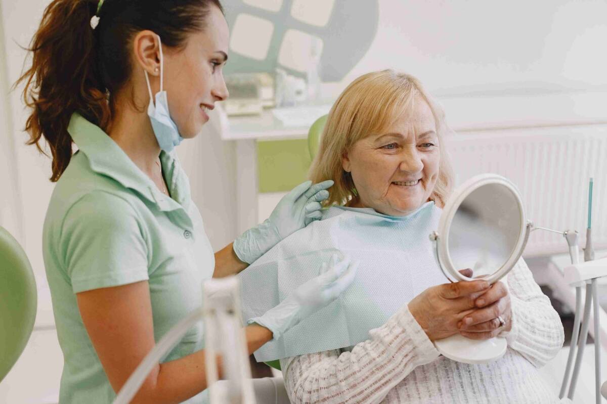 Smiling senior patient looking in a mirror after dental treatment.