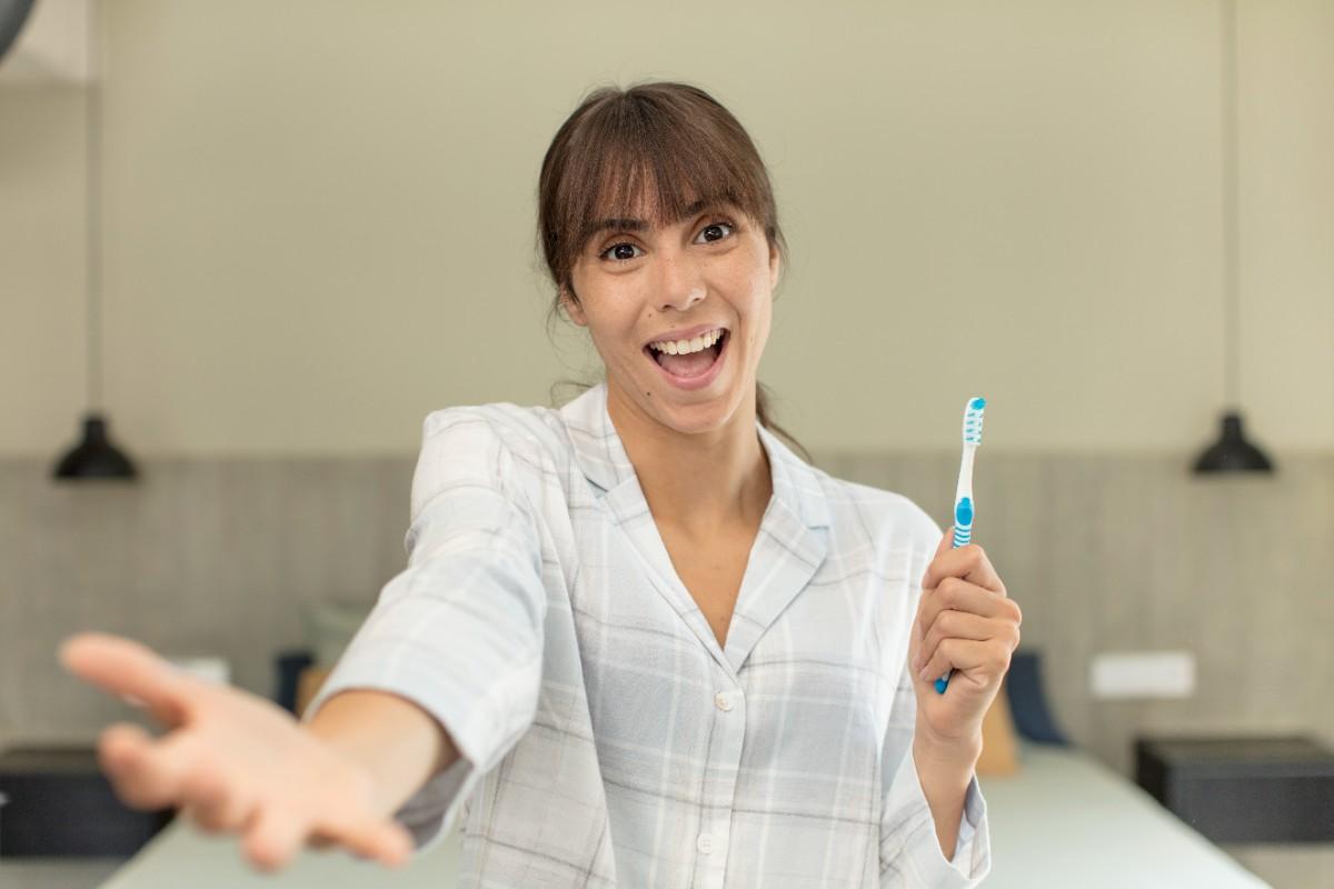 Smiling woman holding a toothbrush, promoting good oral hygiene and daily dental care