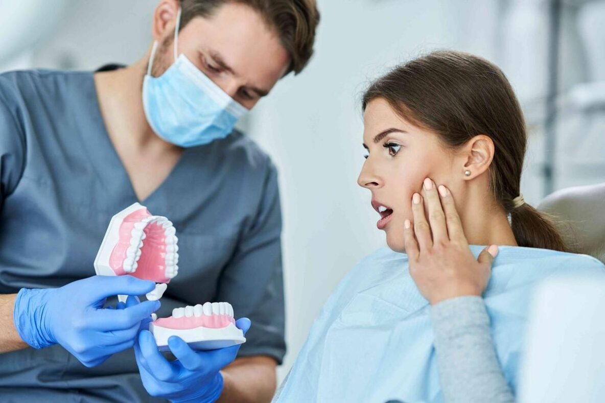 Dentist explaining dental crown and bridge treatment using a dental model