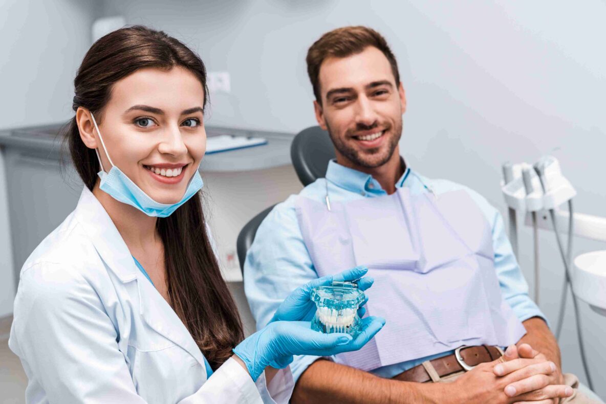 Dentist showing a dental model to a smiling patient.